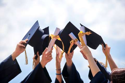 Graduates holding up caps and diplomas